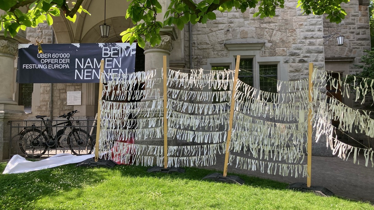 Unzählige Papierstreifen mit unzähligen Namen von verstorbenen Menschen auf der Flucht hängen vor der Kirche Offener St. Jakob in Zürich.