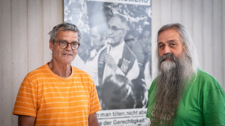 Josef Estermann und Urs Häner vor einem Plakat mit Óscar Romero im langjährigen RomeroHaus.