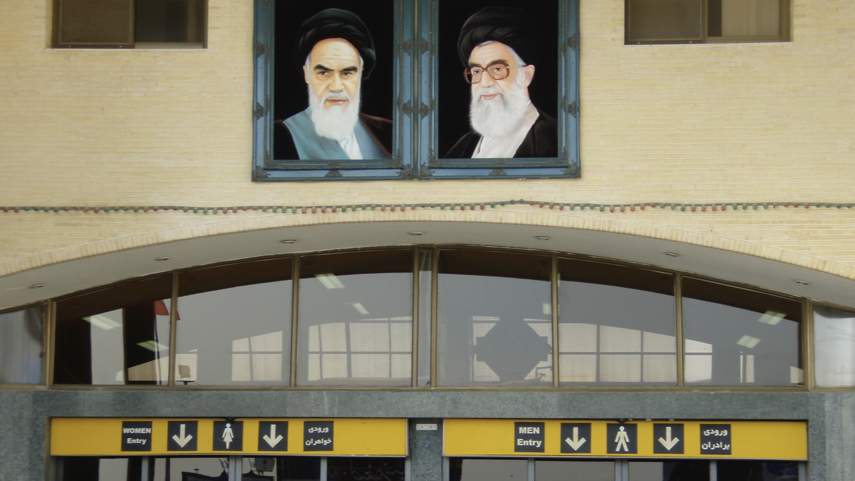 Ein Regime der Angst: Geschlechtergetrennte Kontrolle unter den Porträts von Ruhollah Chomeini und Ali Chamenei am Flughafen in Teheran.