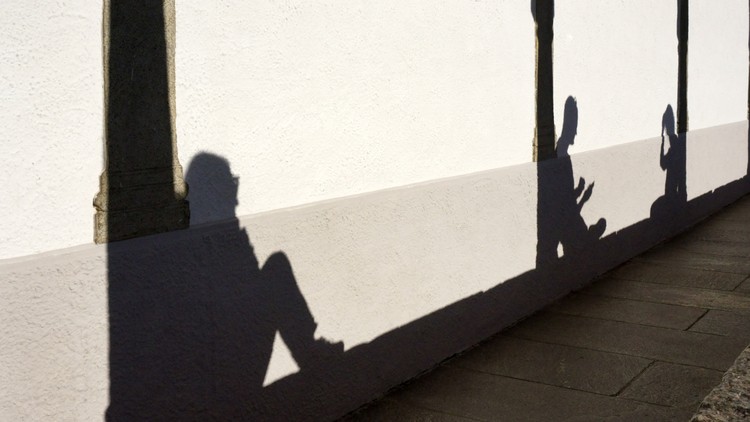 Schatten von Menschen, die sich ausruhen an eine Hauswand geworfen.