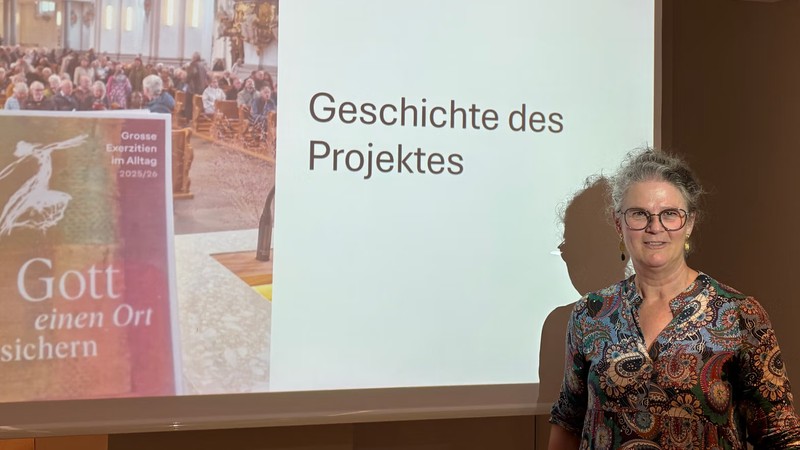 Hildegard Aepli steht neben einer beleuchteten Leinwand ihrer Präsentation