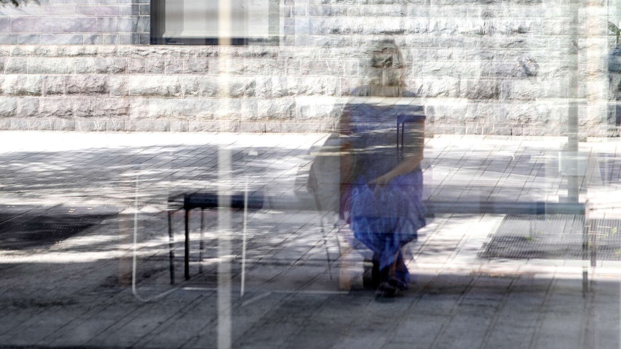 Ein Mensch im verzerrten Spiegel einer Glasscheibe.