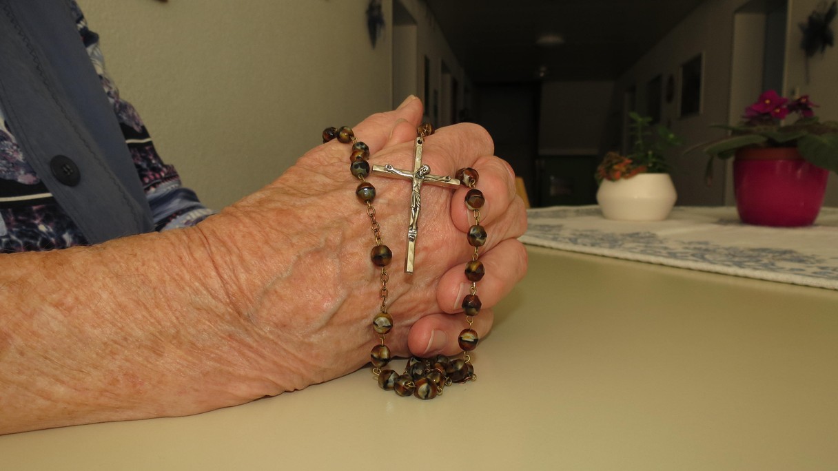 Gefaltete Hände mit Rosenkranz