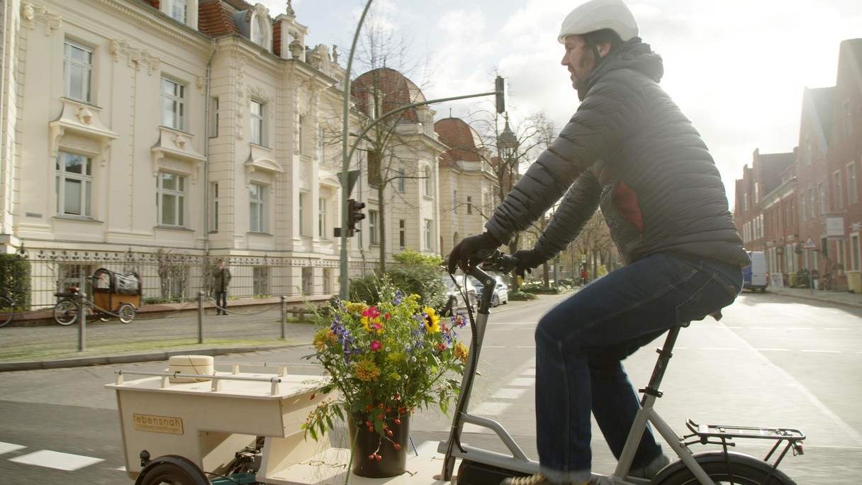 Ein Mann mit einem Lastenvelo transportiert eine Urne.