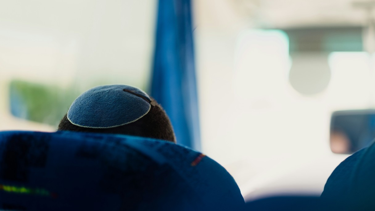 Ein Kopf mit Kippa, von hinten fotografiert in einem Bus.