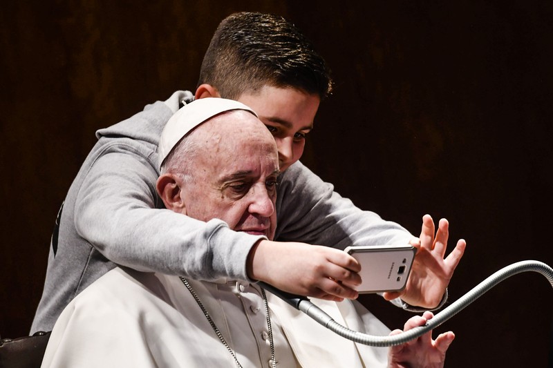 Ein Junge macht ein Selfie mit Papst Franziskus.