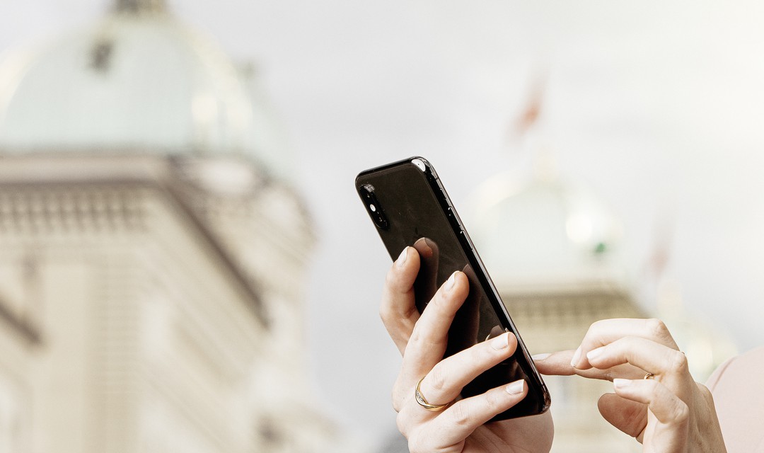 Hand mit Handy vor Bundeshaus.