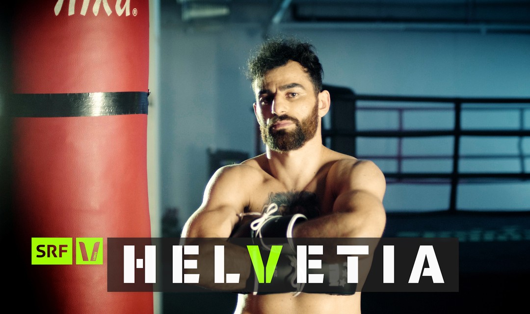 Ando Hakob mit verschränkten Armen im Boxstudio. Überschrift «Helvetia»