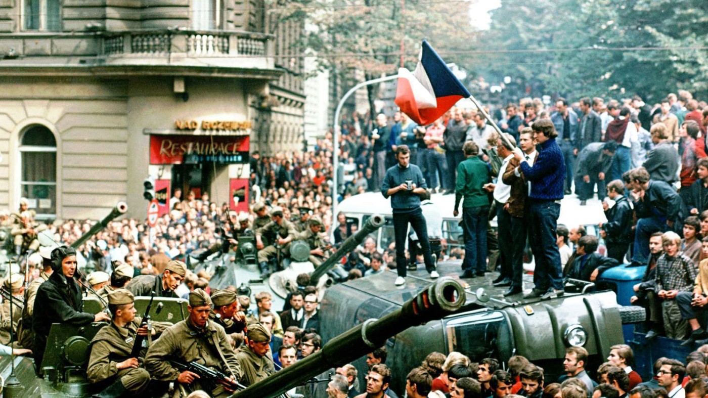 Prager Buerger mit tschechischer Flagge stehen auf einem umgestuerzten Wagen vor einem sowjetischen Panzer am 21. Aug. 1986 in Prag.