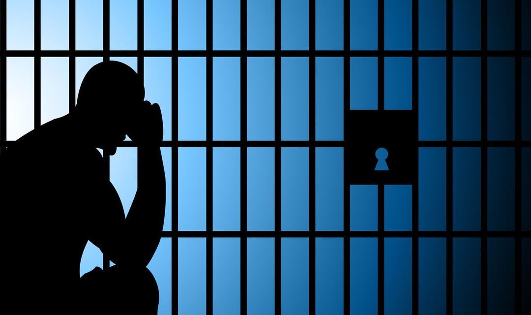 Der Schatten eines Mannes, welcher hinter Gittern sitzt