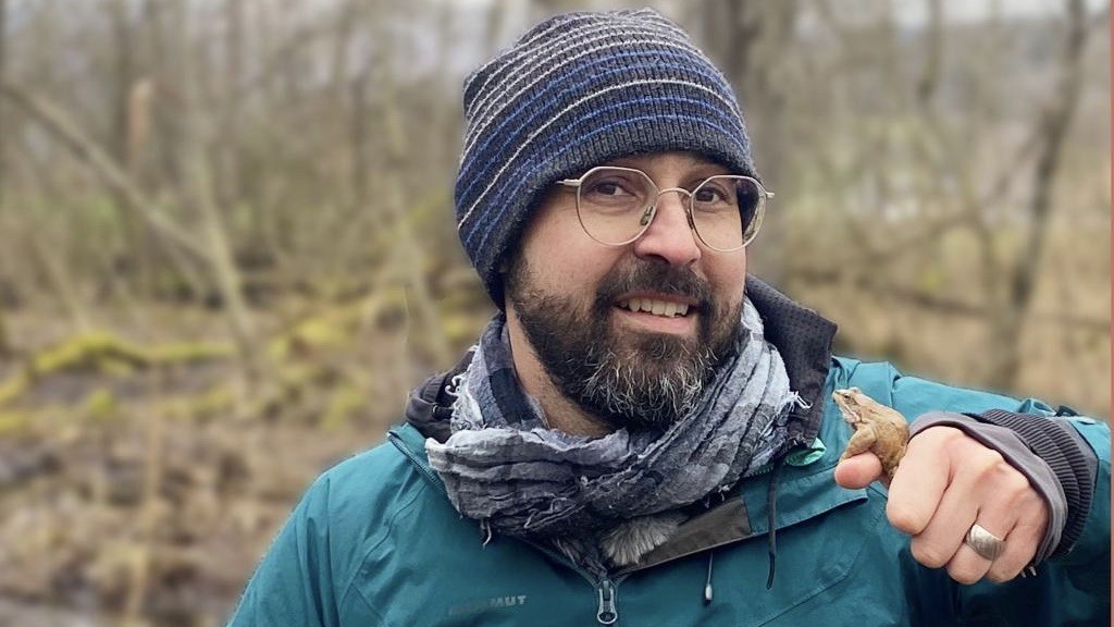 Moderator Bähram Alagheband hält einen Frosch in der Hand.