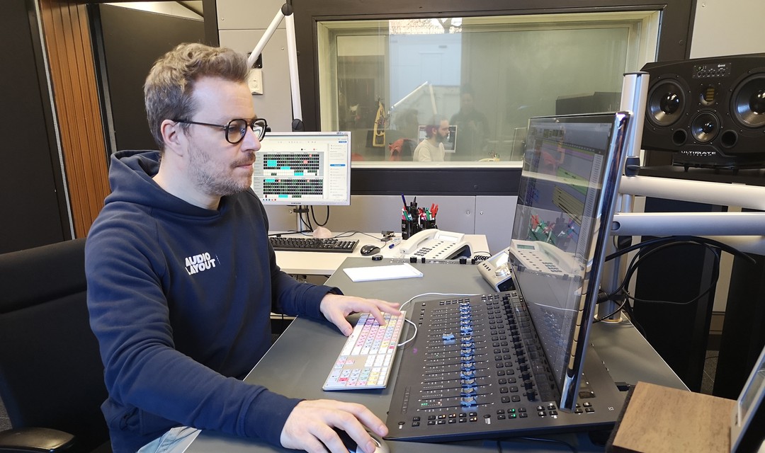 Sascha sitzt im Tonstudio am Bildschirm und bewegt mit der Maus die Audiopegel