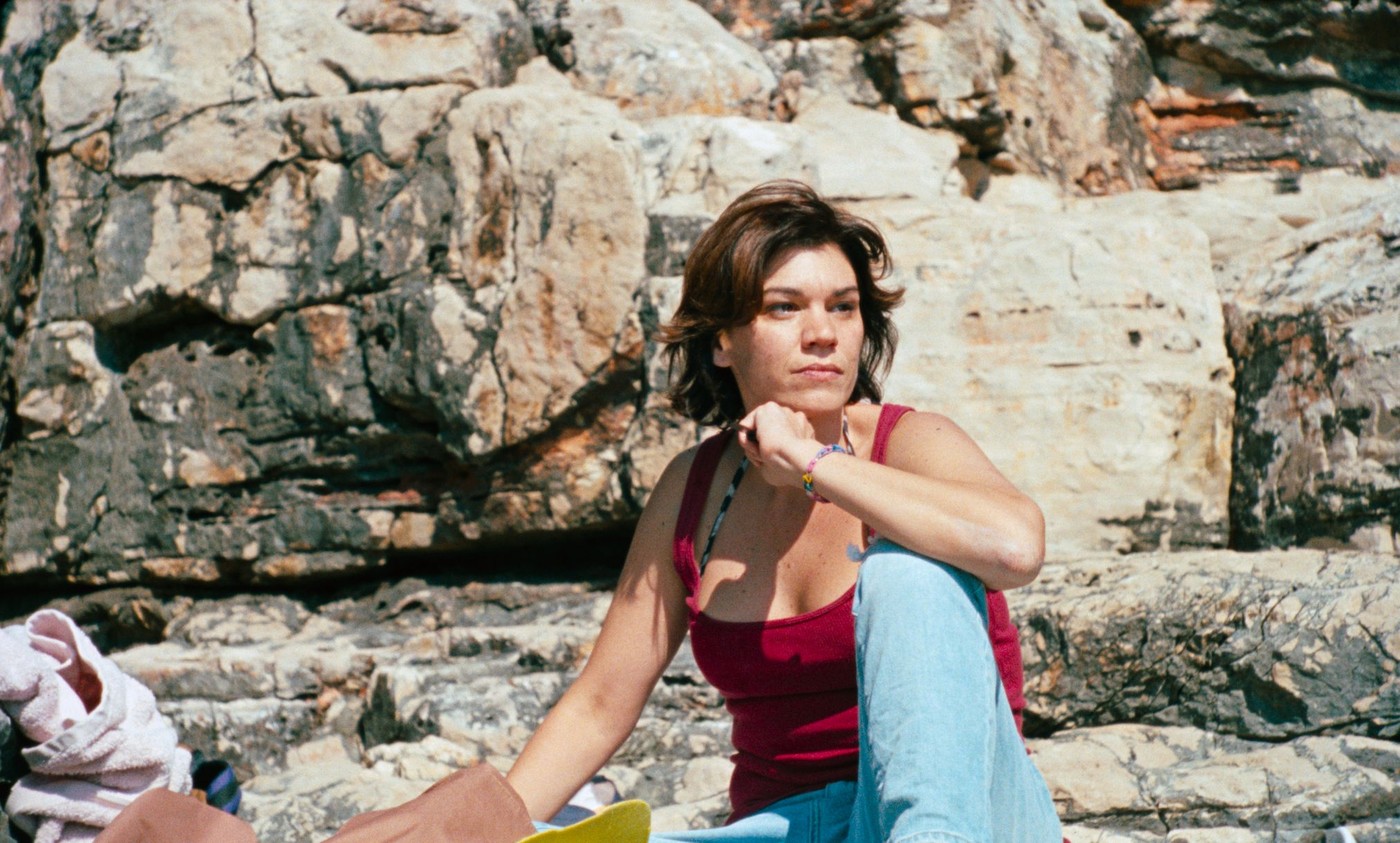 Mare sitzt auf einem Stein am Strand und schaut aufs Meer hinaus