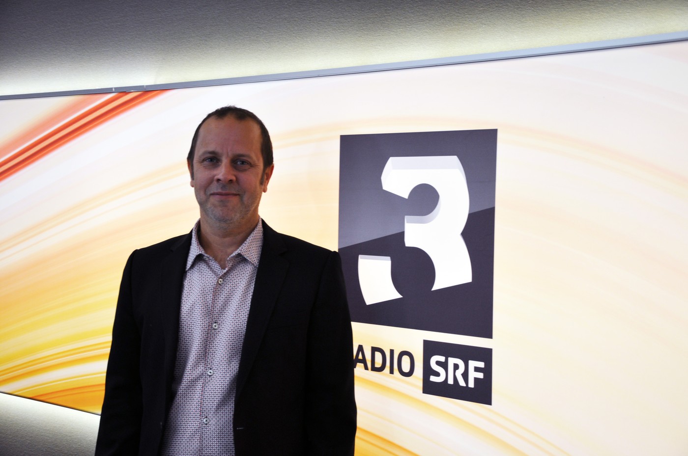 Michael Schuler. Mann mit kurzen schwarzen Haaren, Hemd und Jacket
