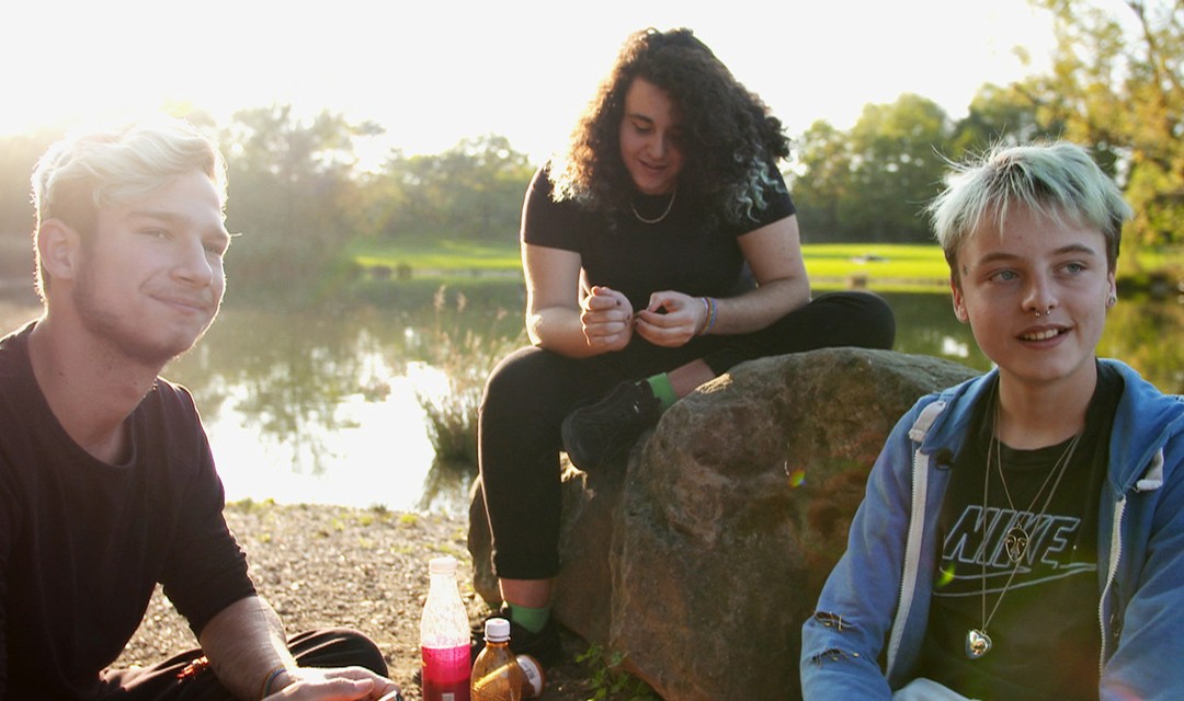Protagonist Emil sitzt mit zwei Freunden an einem Weiher