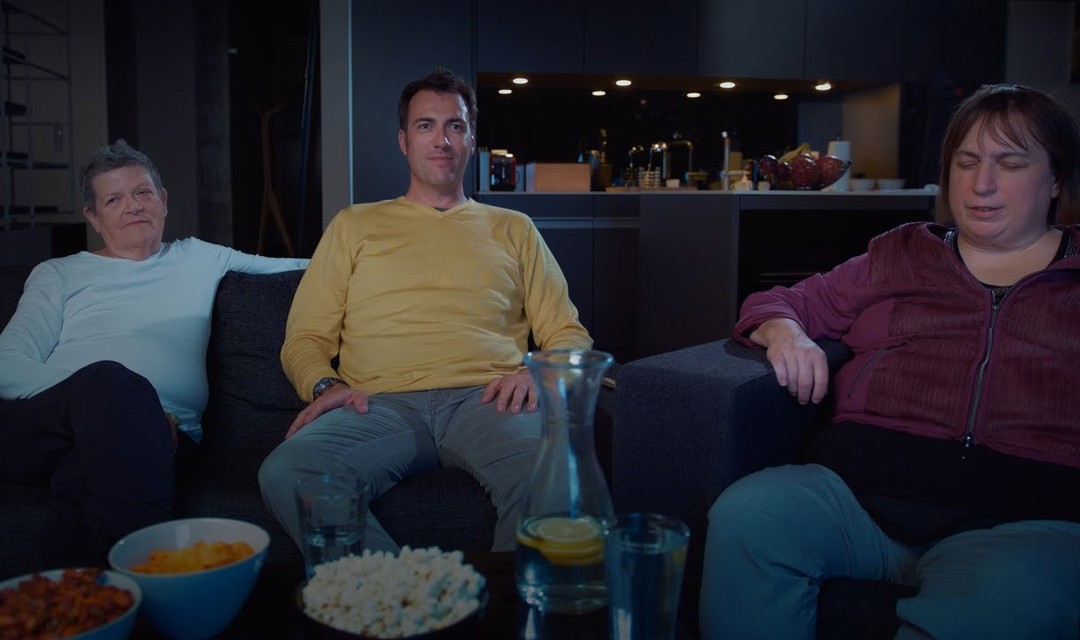 Drei sehbehinderte Personen sitzen auf einem Sofa und schauen Fernseh