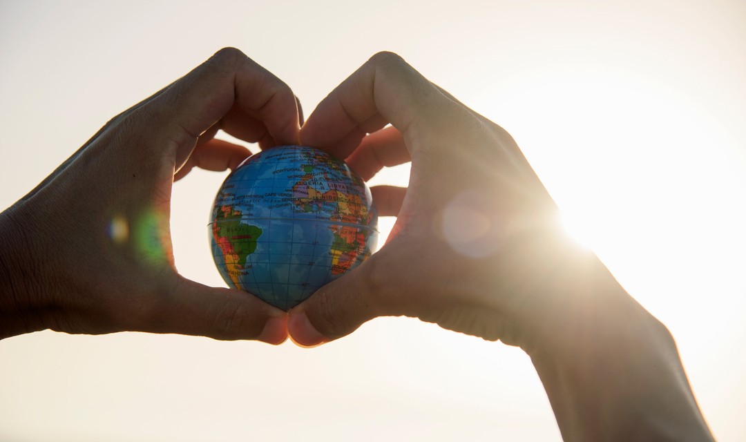 Jemand umfasst mit beiden Händen eine Weltkugel