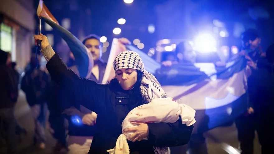 Frau mit weissem Stoffbündel in der Hand und Kreuz aus Klebeband auf dem Mund schwenkt eine Fahne