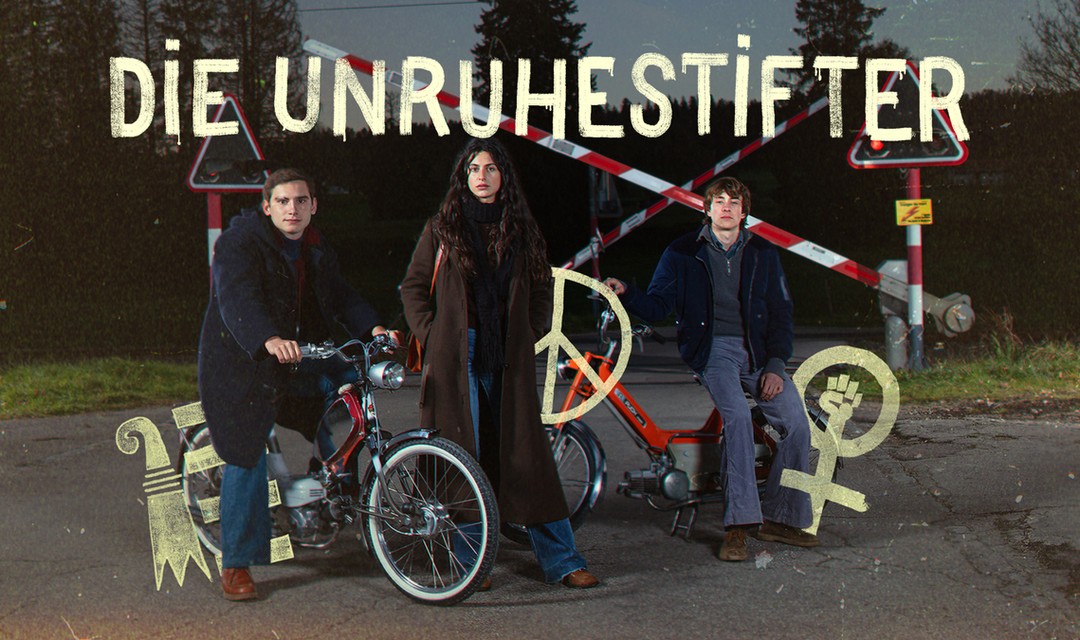 Foto der Hauptdarstellenden vor einem Bahnübergang