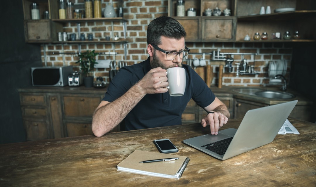 Ein Mann sitzt an einem Tisch und arbeitet an seinem Computer.