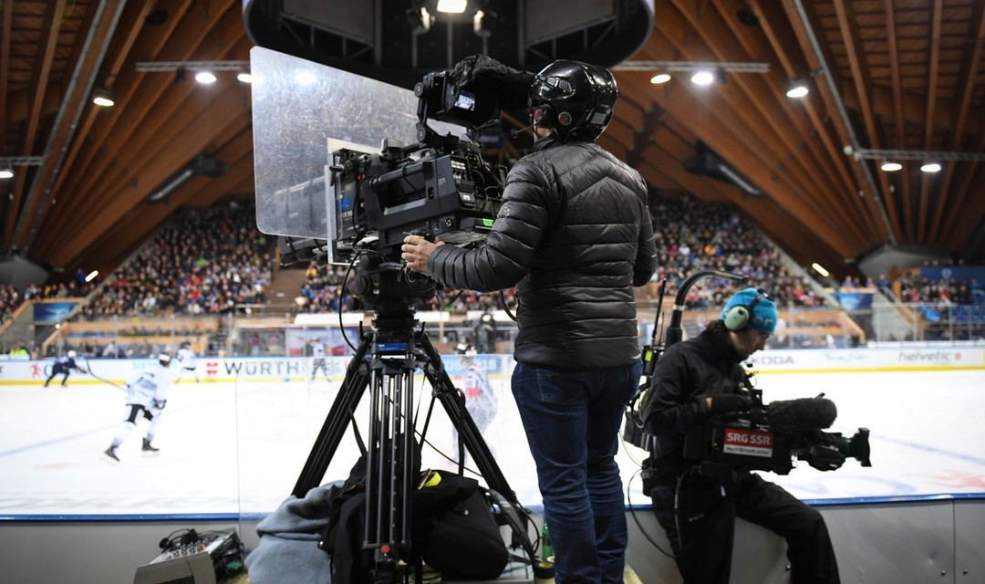 Bild eines Kamermannes, welcher ein Eishockeyspiel