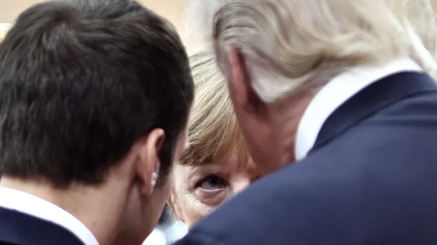 Angela Merkel verdeckt von Donald Trump und zweiter Person