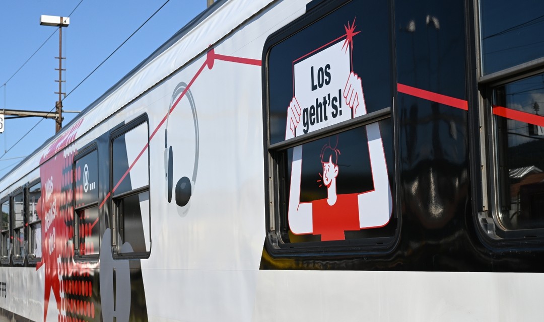 SBB-Zug, auf der Scheibe ein Aufkleber, auf dem steht "Los geht's!"