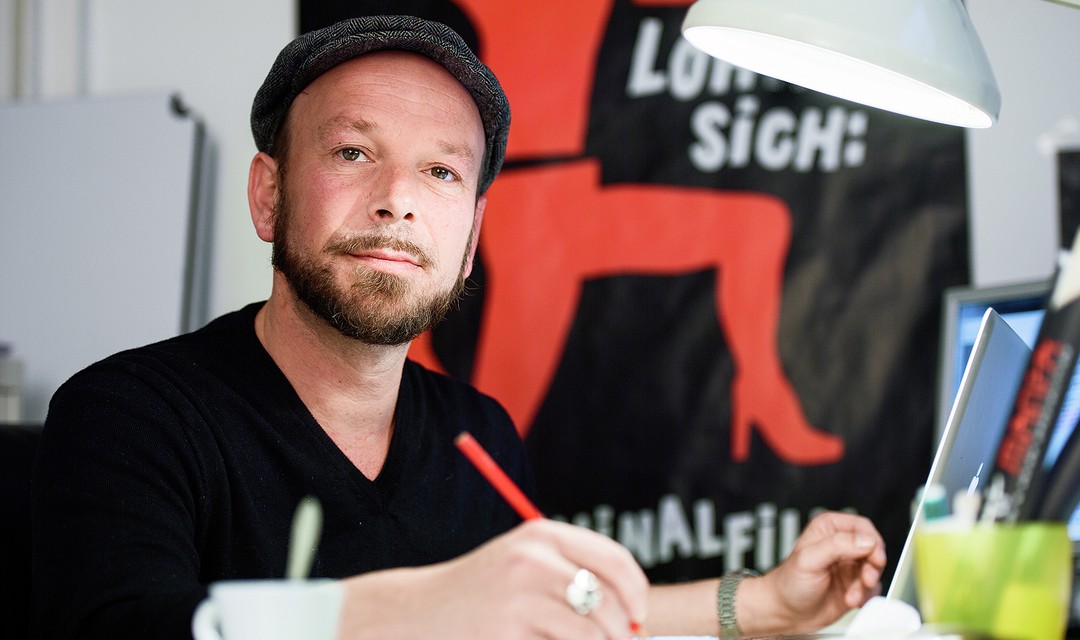 Drehbuchautor Dave Tucker sitzt am Pult und schreibt an einem Drehbuch